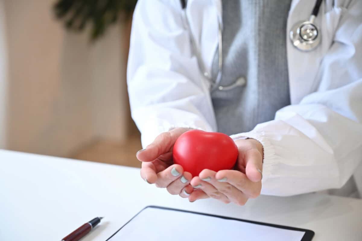 Female doctor holding red heart shape in hand. Cardiology concept.