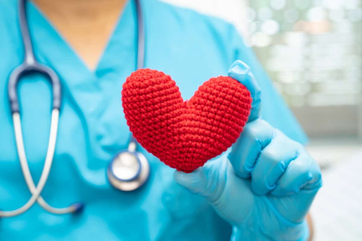 Doctor holding a red heart in hospital ward, healthy strong medical concept.