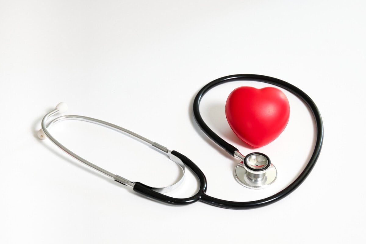 red heart surrounded by black stethoscope on the right side of the image on white background