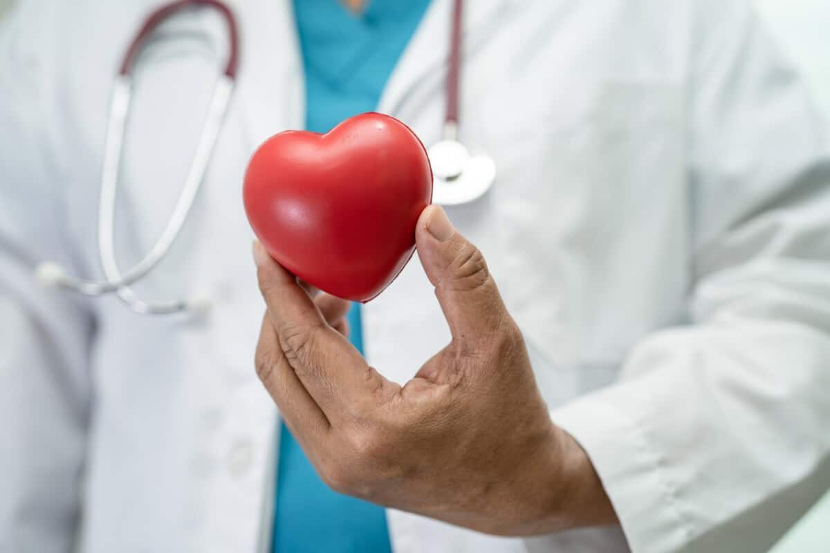 Doctor holding a red heart in hospital ward, healthy strong medical concept.